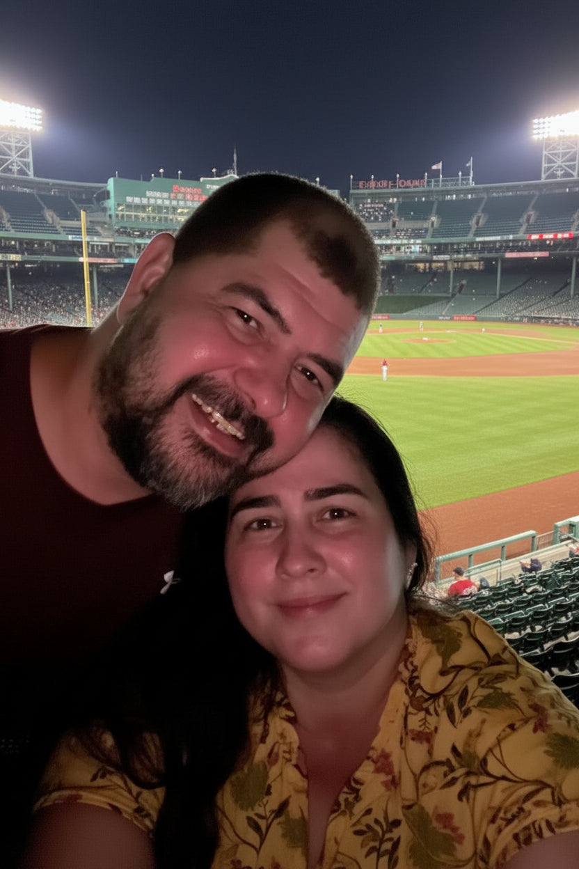 Man and woman posing close together, smiling with baseball caps on outdoors